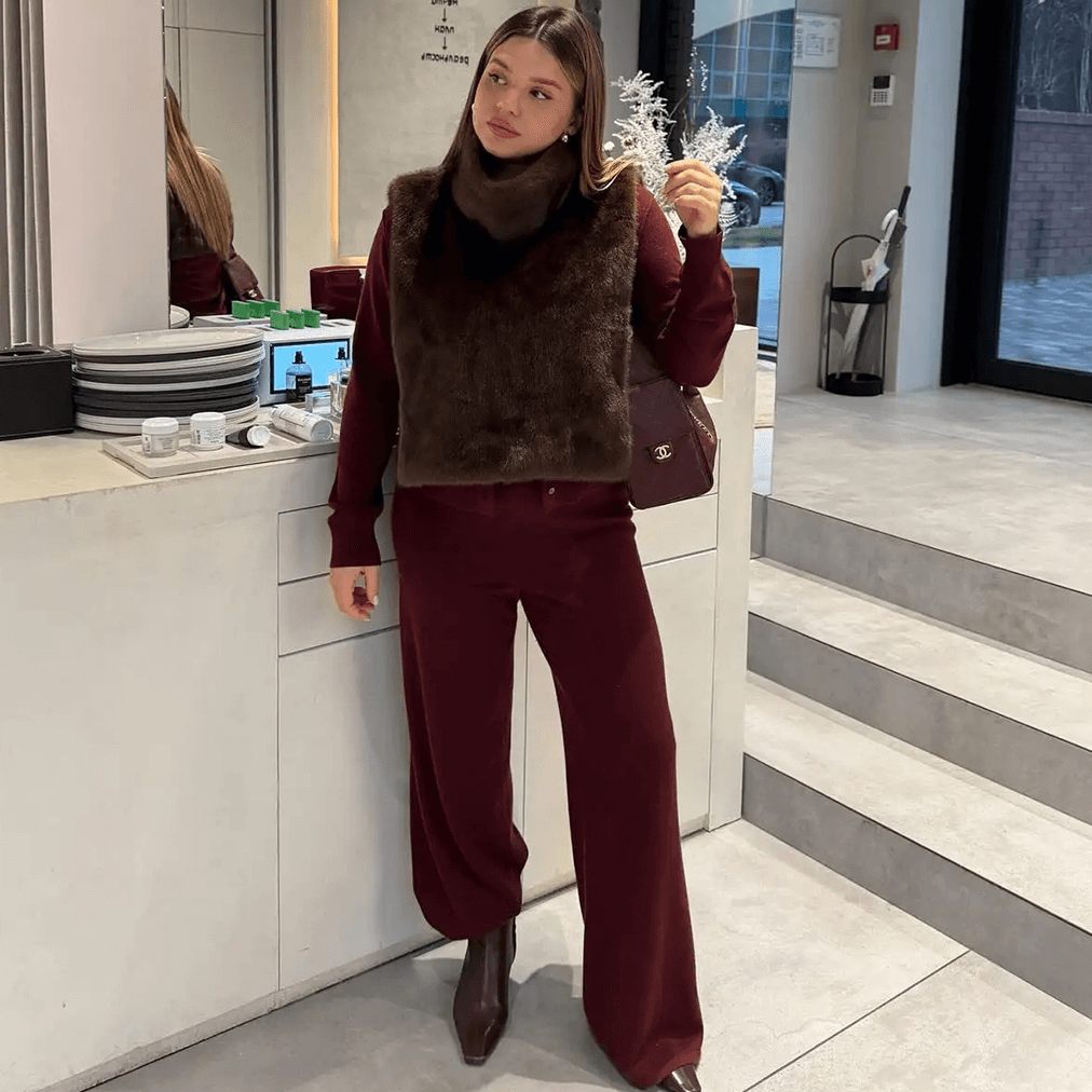 Woman in a maroon outfit standing in a modern interior setting